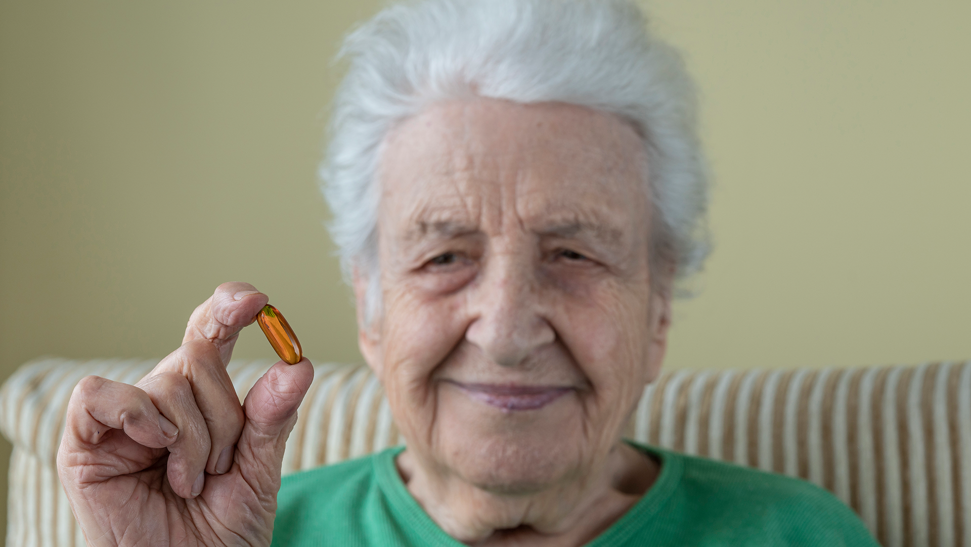 Ältere Frau hält Tablette in der Hand – die PflegeInsel unterstützt bei der Medikamenteneinnahme.